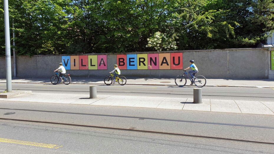 Drei Kinder auf Velos fahren in Wabern an der Villa Bernau vorbei.