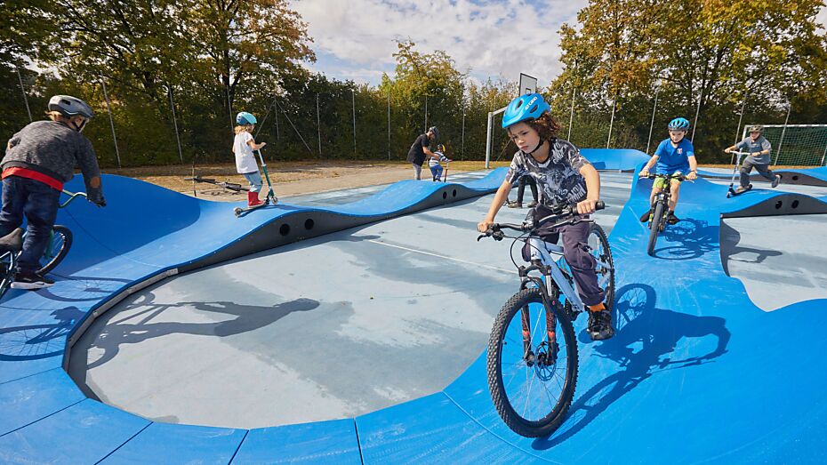 Aufgestellter Pumptrack in der Schule Buchseegut, der von Kindern mit verschiedenen Geräten befahren wird.
